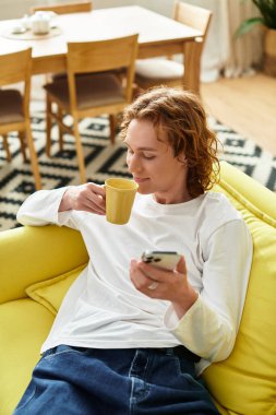 Yakışıklı bir genç adam evde uzanırken, arkadaşlarıyla sohbet ederken sıcak bir içecekten hoşlanır..