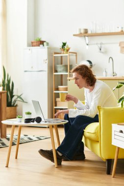 Parlak ve davetkar ev ortamında elinde kahveyle çalışan genç bir adam görülüyor..