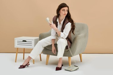 Uzun kahverengi saçlı güzel bir kadın. Samimi bir stüdyo ortamında şık bir kıyafet..