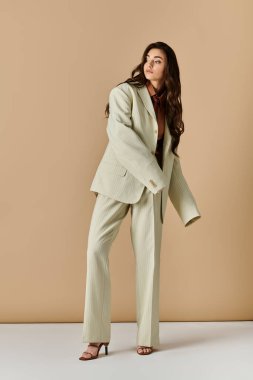 Şık bir genç kadın kravat takmış, stüdyoya güvenerek poz veriyor..