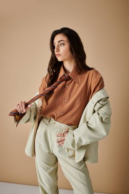 Uzun kahverengi saçlı, kendine güveni tam genç bir kadın modaya uygun bir şekilde poz veriyor..