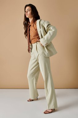 Kendine güvenen, şık takım elbiseli genç bir kadın uzun kahverengi saçlarıyla zarafet saçar..