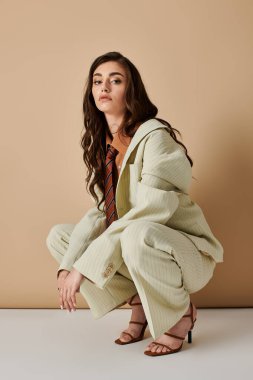 Kendine güvenen genç bir kadın zarif bir poz verirken şık bir takım elbise ve kravatla eşsiz tarzını sergiliyor..