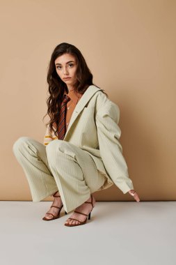 Şık bir genç kadın şık kıyafetlerini ve zarif pozunu şık bir stüdyoda sergiliyor..