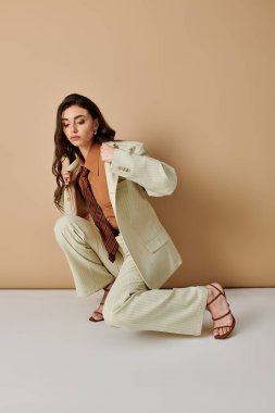 Kendine güvenen genç bir kadın şık bir kıyafet içinde stüdyoda kendine has tarzını sergiliyor..