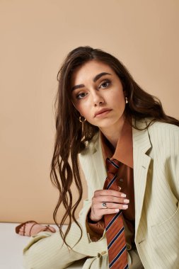 Güzel genç bir kadın şık bir takım elbiseyle şık bir şekilde poz veriyor..