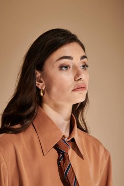 Kendine güvenen bir kadın şık bir stüdyoda modern tarzını şık bir kıyafet ve kravatla sergiliyor..