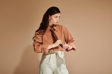 Genç bir kadın şık bir stüdyoda şık kıyafetlerini ayarlarken kendine güveni tam..