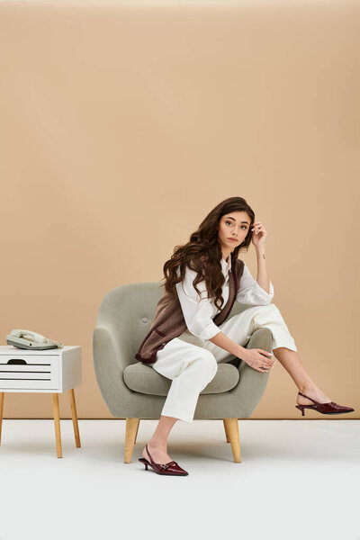 Молодая женщина, одетая в модную одежду, изящно сидит на стуле, излучая уверенность.