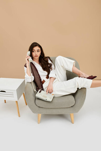 Расслабляясь в стильном кресле, она воплощает современную моду с изяществом и элегантностью.