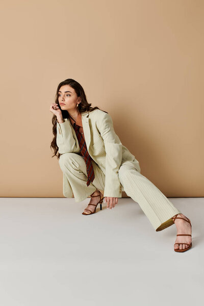 A young woman with long brown hair poses in a fashionable suit and tie