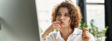 Kıvırcık saçlı genç iş kadını, şık kıyafetleri ve afişiyle özenle çalışır.