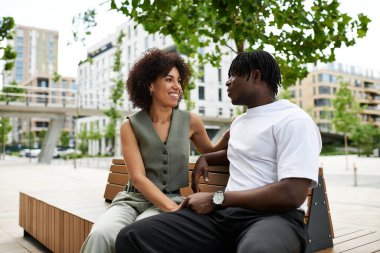 Genç bir çift canlı bir şehir parkında neşeli bir anı paylaşıyor, gülüyor ve bağ kuruyor..