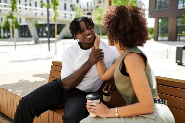 Genç bir çift kenarda oturup güneşli bir günde gülücüklerini ve içkilerini paylaşıyor..