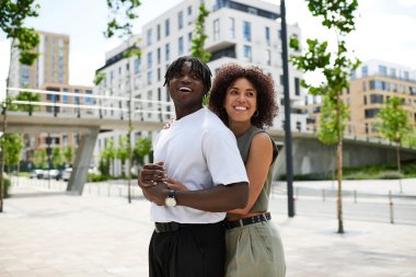 Genç çift güneşli bir günde şehir manzarasını keşfederken neşeli bir anı paylaşıyor..