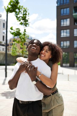 Genç bir çift canlı bir şehir ortamında mutlu bir şekilde kucaklaşır ve özel randevularını yakalar..
