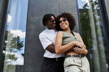 Genç bir adam ve kadın birlikte neşeli bir anı paylaşıyorlar. Şık bir yaz kıyafeti giyiyorlar..