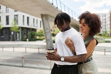 Moda kıyafetleri içinde bir çift şehir manzarasını keşfederken neşeli bir anı paylaşıyor..