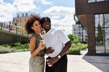 Genç adam ve kadın, canlı bir şehir ortamında buluşmalarının tadını çıkarırken gülüşüyorlar..