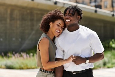 Genç çift güneşli bir günde şehir manzarasını keşfederken neşeli bir anı paylaşıyor..