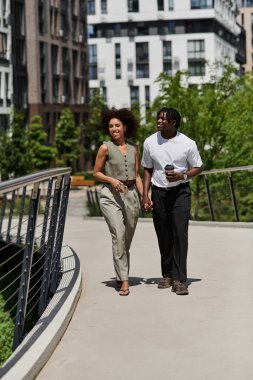 Genç bir Afrikalı Amerikalı çift, canlı bir şehir bölgesinde el ele yürür, gülümserler..