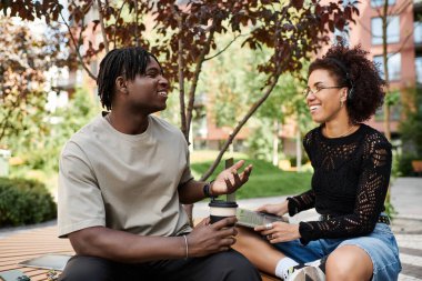 Genç bir Afrikalı Amerikalı çift güneşli bir yaz gününde şehir parkında uzaktan çalışırlar..