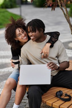 Genç bir çift dizüstü bilgisayarlarda çalışıyor, şehirde canlı bir yaz havasının tadını çıkarıyorlar..