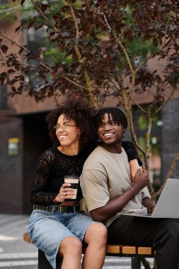 Genç Afrikalı Amerikalı çift, canlı bir şehir atmosferinde uzaktan birlikte çalışmaktan zevk alıyor..