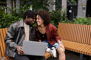 Genç çift bir şehir parkında çalışmaktan zevk alıyor, bir projede çalışırken gülümsemelerini paylaşıyorlar..