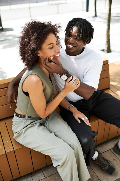 A young couple, dressed in trendy outfits, share joyful moments in the heart of the city.