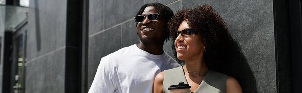 Молодая пара, одетая в модные наряды, делится смехом, исследуя городской пейзаж, баннер