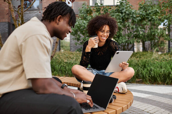 A stylish young couple enjoys a productive day working remotely together in the city greenery.