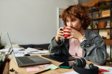 Genç bir kadın yaz boyunca parlak bir dairede dizüstü bilgisayarla çalışırken içmekten zevk alıyor..