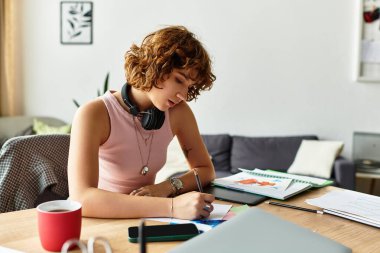 Kıvırcık saçlı genç bir kadın kendini notların ve çizimlerin arasında yaratıcı bir işe sokuyor..