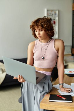 Kıvırcık saçlı genç bir kadın yaz günlerinde rahat dairesinde özenle çalışıyor..