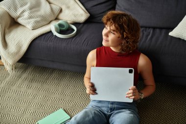 Genç bir kadın rahat bir dairede, dinlenirken bir tabletle meşgul olmak hoşuna gidiyor..