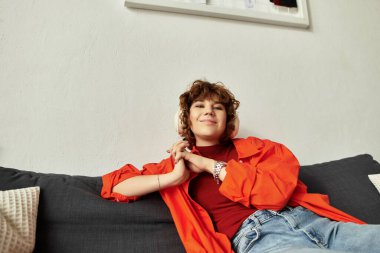 Kıvırcık saçlı kadın koltuğunda dinleniyor, şık mekânında rahat bir yaz havasını kucaklıyor..