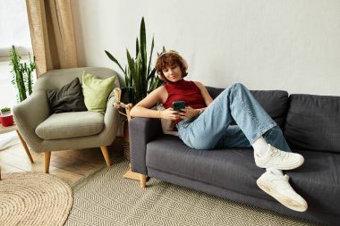 Rahat bir şekilde kıvrılarak, genç bir kadın telefonunu modern bir ortamda kontrol ederken rahatlar..