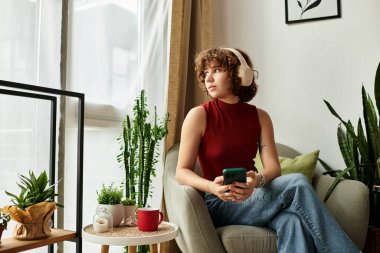 Kıvırcık saçlı genç bir kadın rahat dairesinde telefonuyla meşgul..