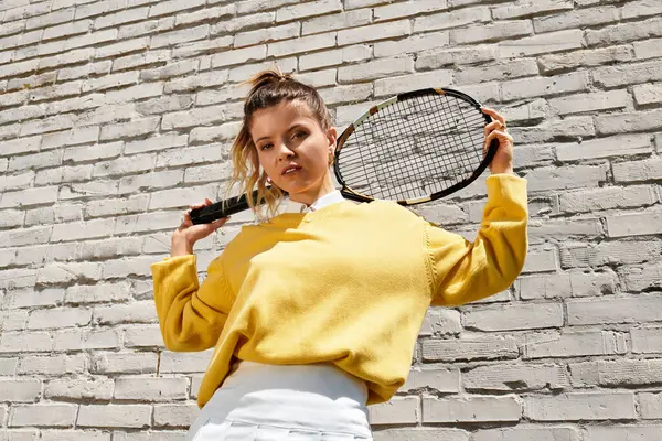 Genç ve güzel bir kadın, yaz ruhunu sergileyerek, tenis raketiyle rahatça poz veriyor..