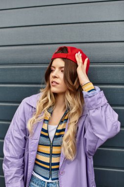 Çekici genç bir kadın dokulu bir duvara yaslanmış, yaz cazibesi ve kendine güveni yayıyor..