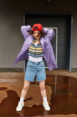 Neşeli giyinmiş neşeli genç bir kadın neşeli bir ruhla güneşli bir günün tadını çıkarıyor.