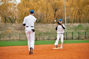 Gençlik, ağaçlarla çevrili ve enerji dolu canlı bir sahada beysbol antrenmanı yapıyor..