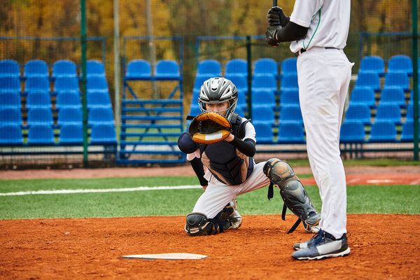 Два преданных подростка активно играют в бейсбол на ухоженном поле под ясным небом.