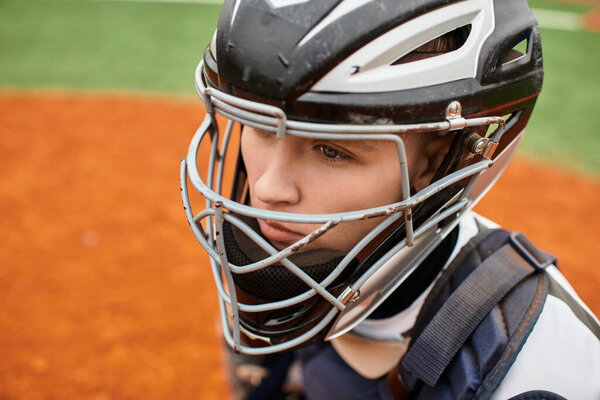 A young athlete focuses intently on the game while wearing a baseball helmet and gear.