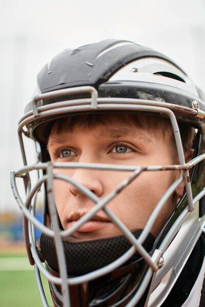 Решительный подросток в шлеме ловца стоит готовый на поле для подачи.