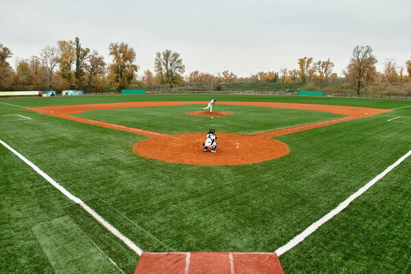 Two teenage boys compete fiercely in a baseball game on a vibrant green field as autumn leaves fall.