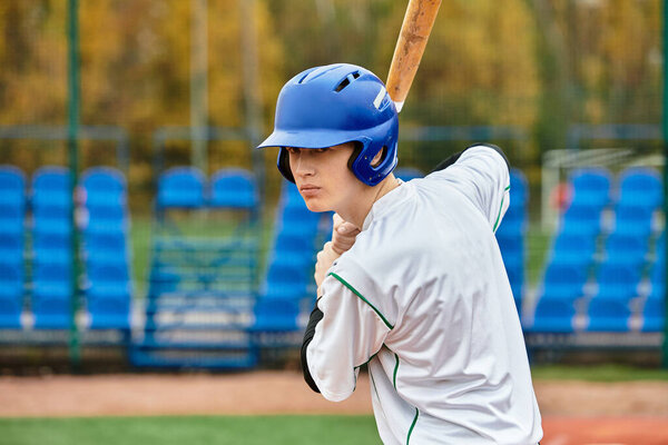 A confident player stands ready at bat on a sunny baseball field surrounded by bleachers.