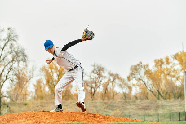 A talented young athlete demonstrates his pitching technique on a baseball field during autumn.