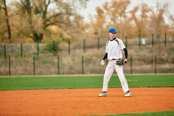 Самоотверженный подросток стоит на бейсбольном поле, сосредоточенный на игре под открытым небом.